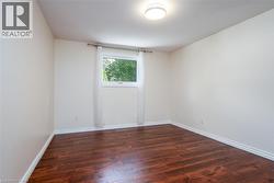 Unfurnished room featuring dark wood finished floors and baseboards - 
