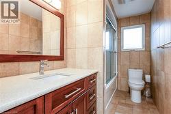 Bathroom with tile walls, vanity, and combined bath / shower with glass door - 