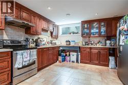 Kitchen featuring stainless steel appliances, under cabinet range hood, tasteful backsplash, recessed lighting, and brown cabinetry - 