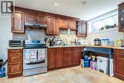Kitchen featuring stainless steel range with electric stovetop, under cabinet range hood, decorative backsplash, white microwave, and brown cabinets - 