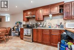 Kitchen featuring stainless steel electric stove, decorative backsplash, under cabinet range hood, white microwave, and recessed lighting - 