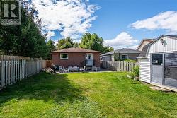 Back of property with a patio area, a fenced backyard, a shed, and brick siding - 