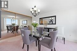 Dining room featuring a chandelier and light colored carpet - 