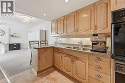 Kitchen featuring crown molding, light colored carpet, dark stone counters, a peninsula, and a breakfast bar area - 