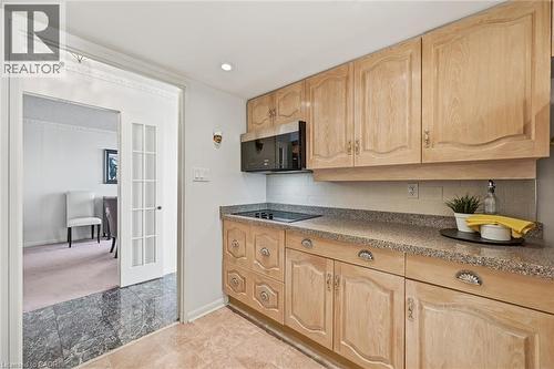 Kitchen with light brown cabinets, stainless steel microwave, backsplash, dark stone countertops, and recessed lighting - 2170 Marine Drive Unit# 1808, Oakville, ON - Indoor Photo Showing Kitchen