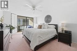 Bedroom with a textured ceiling, light colored carpet, a ceiling fan, and floor to ceiling windows - 