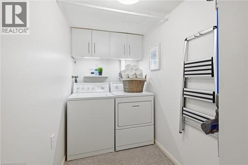 Laundry room with light colored carpet, cabinet space, washer and dryer, and radiator heating unit - 2170 Marine Drive Unit# 1808, Oakville, ON - Indoor Photo Showing Laundry Room