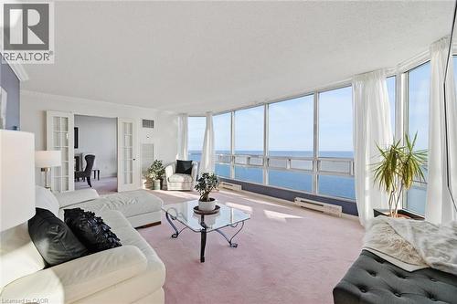 Living room with french doors, a water view, carpet, a textured ceiling, and a baseboard heating unit - 2170 Marine Drive Unit# 1808, Oakville, ON - Indoor Photo Showing Living Room