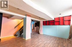 Unfurnished living room with a textured ceiling, wood finished floors, stairs, and independent washer and dryer - 