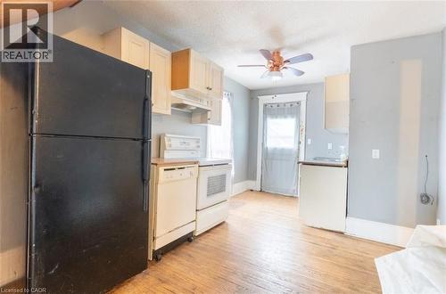 Kitchen with white appliances, a textured ceiling, light wood-style floors, under cabinet range hood, and ceiling fan - 219 Erie Avenue, Brantford, ON - Indoor Photo Showing Kitchen
