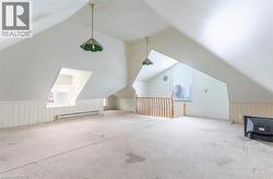 Additional living space featuring lofted ceiling, healthy amount of natural light, baseboard heating, and wainscoting - 