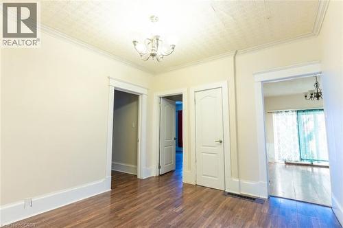 Spare room featuring a chandelier, ornamental molding, and dark wood-style floors - 219 Erie Avenue, Brantford, ON - Indoor Photo Showing Other Room