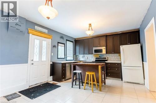 Kitchen featuring dark brown cabinets, freestanding refrigerator, a kitchen island, hanging light fixtures, and tasteful backsplash - 219 Erie Avenue, Brantford, ON - Indoor Photo Showing Kitchen