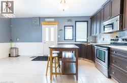 Kitchen featuring appliances with stainless steel finishes, dark brown cabinets, light countertops, tasteful backsplash, and hanging light fixtures - 
