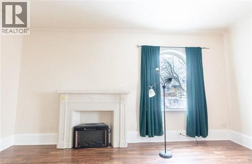 Unfurnished living room featuring wood finished floors and crown molding - 219 Erie Avenue, Brantford, ON - Indoor With Fireplace