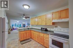 Kitchen with white appliances, open floor plan, light brown cabinetry, and under cabinet range hood - 