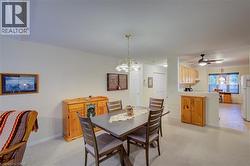 Dining space featuring a chandelier, a ceiling fan, and light carpet - 