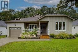 View of front of home with covered porch, a front yard, and an attached garage - 