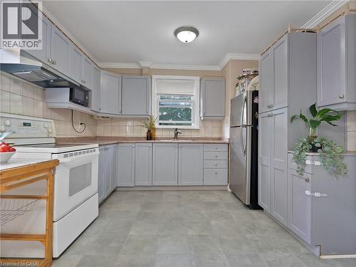 Kitchen with white range with electric cooktop, tasteful backsplash, ornamental molding, under cabinet range hood, and freestanding refrigerator - 210 East 24Th Street, Hamilton, ON - Indoor Photo Showing Kitchen