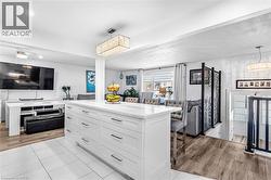 Kitchen with open floor plan, white cabinetry, a center island, and light stone counters - 