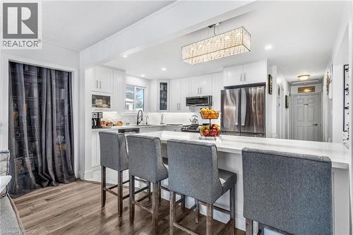 Kitchen featuring a kitchen bar, appliances with stainless steel finishes, white cabinets, light wood-style flooring, and a peninsula - 136 Limpert Avenue, Cambridge, ON - Indoor Photo Showing Other Room