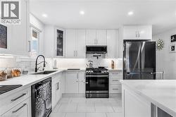 Kitchen featuring appliances with stainless steel finishes, white cabinets, light stone countertops, recessed lighting, and light tile patterned flooring - 
