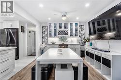 Kitchen featuring freestanding refrigerator, white cabinets, light stone counters, glass insert cabinets, and light wood finished floors - 