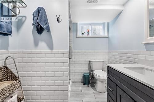 Full bath with a wainscoted wall, vanity, tile walls, and a stall shower - 136 Limpert Avenue, Cambridge, ON - Indoor Photo Showing Bathroom