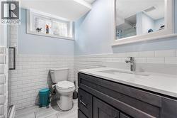 Full bathroom featuring a shower stall, vanity, a wainscoted wall, and tile walls - 