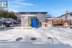Snow covered back of property with a fenced backyard, a hot tub, a gazebo, a patio, and an outbuilding - 