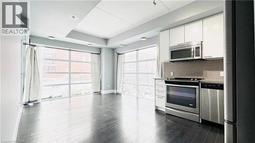 Kitchen with stainless steel appliances, white cabinets, light countertops, and decorative backsplash - 155 St. Leger Unit# 107, Kitchener, ON - Indoor Photo Showing Kitchen