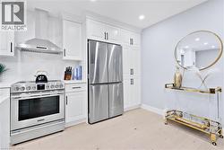 Kitchen featuring stainless steel appliances, wall chimney exhaust hood, white cabinets, recessed lighting, and light wood-style floors - 