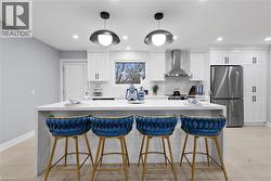 Kitchen featuring a breakfast bar, freestanding refrigerator, white cabinetry, light stone counters, and a kitchen island - 