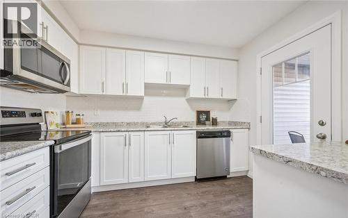 Kitchen featuring appliances with stainless steel finishes, white cabinets, and dark wood finished floors - 24 Morrison Road Unit# D9, Kitchener, ON - Indoor Photo Showing Kitchen With Double Sink With Upgraded Kitchen
