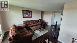 Living area featuring dark finished floors, a baseboard heating unit, and a textured ceiling - 