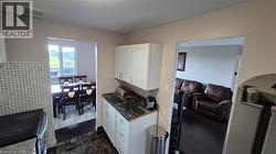 KKitchen featuring stainless steel appliances, white cabinetry, dark finish floors, tasteful backsplash, and countertops - 