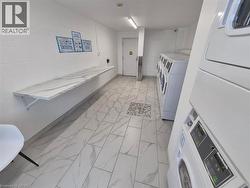 Shared laundry featuring washer and dryer, light marble finish flooring, and concrete block wall - 