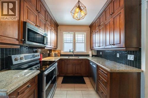Kitchen with appliances with stainless steel finishes, light stone counters, tasteful backsplash, light tile patterned floors, and hanging light fixtures - 184 Weber Street E, Kitchener, ON - Indoor Photo Showing Kitchen