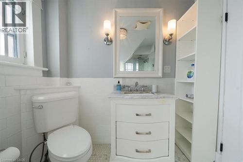 Half bath with a wainscoted wall, vanity, tile walls, healthy amount of natural light, and light tile patterned flooring - 184 Weber Street E, Kitchener, ON - Indoor Photo Showing Bathroom