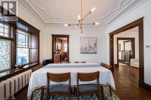 Dining space featuring radiator heating unit, a chandelier, crown molding, a textured ceiling, and parquet flooring - 184 Weber Street E, Kitchener, ON - Indoor Photo Showing Dining Room