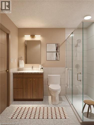 Bathroom featuring tile walls, vanity, a shower stall, a textured ceiling, and a wainscoted wall - 580 Coldstream Drive Unit# 310, Waterloo, ON - Indoor Photo Showing Bathroom