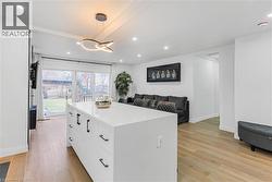 Kitchen featuring white cabinets, decorative light fixtures, light wood-style flooring, open floor plan, and recessed lighting - 