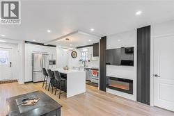 Kitchen featuring appliances with stainless steel finishes, a kitchen bar, a center island, decorative light fixtures, and light wood-style flooring - 