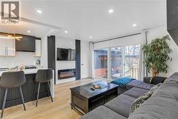 Living area with a large fireplace, light wood finished floors, and recessed lighting - 