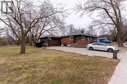 View of home's exterior featuring a chimney, brick siding, driveway, a yard, and a garage - 