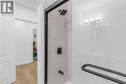 Full bathroom featuring light wood-style flooring and shower / bath combination with glass door - 