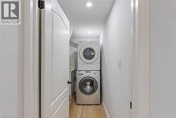 Washroom featuring estacked washer and dryer, light wood finished floors, and recessed lighting - 