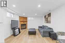 Living room featuring light wood finished floors, a brick fireplace, and recessed lighting - 