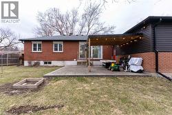 Back of property featuring brick siding, a lawn, and a wooden deck - 