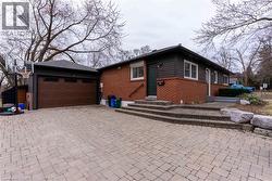 View of front of house with decorative driveway, brick siding, and an attached garage - 